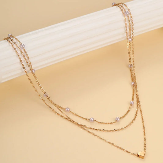 Gold necklace with heart charm on a beige background
