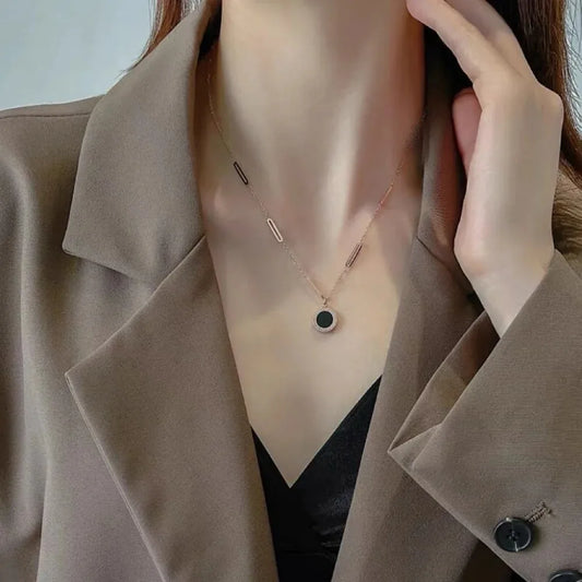 Necklace with a pendant worn by a person in a beige coat.