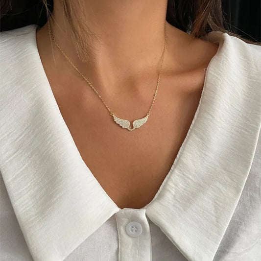 Gold necklace with a delicate pendant worn by a person in a white shirt.