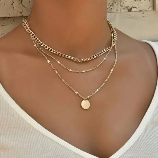 Gold chain necklaces on a person wearing a white top.