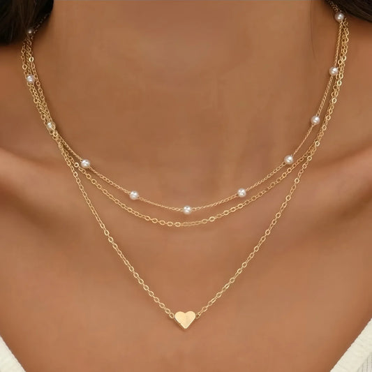 Gold necklace with heart pendant on a model against a neutral background