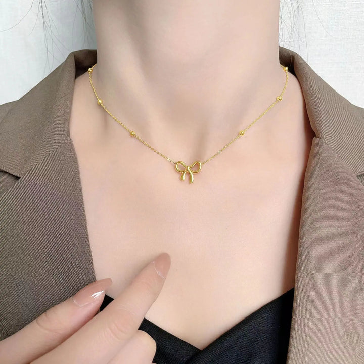 Gold-tone bow charm jewelry set with necklace, bracelet and earrings